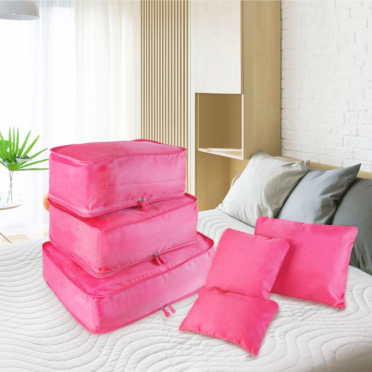 hot pink packing cubes and pouches laid out on a bed